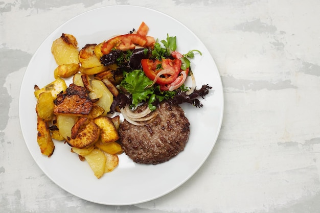 Foto vers gegrilde hamburgers met aardappel en salade in kleine kom