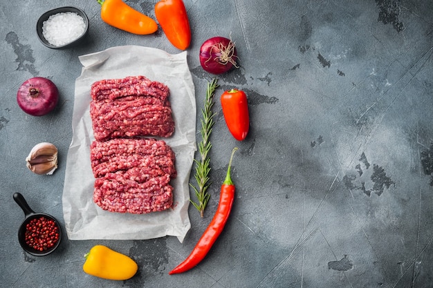 Vers gehakt vlees, rundergehakt, op grijze tafel, bovenaanzicht plat lag met kopie ruimte