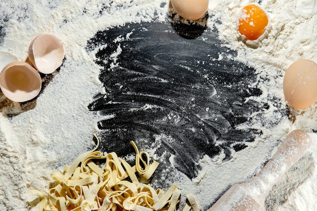 Vers gekookte pasta ligt op een donker met bloem bestrooid oppervlak. italiaanse pasta. tagliatelle. bovenaanzicht, kopieer ruimte.