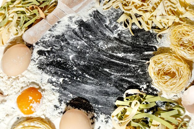 Vers gekookte pasta ligt op een donker oppervlak bestrooid met bloem Italiaanse pasta Tagliatelle Rauwe pasta Italiaans pastarecept Bovenaanzicht kopieerruimte