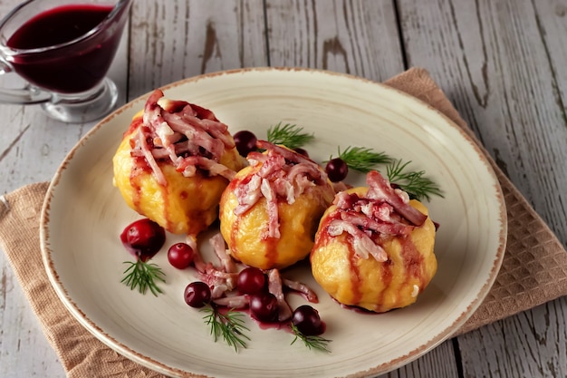 Vers gekookte Zweedse aardappelbollen met cranberrysaus op een lichte achtergrond.