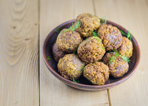 Vers gemaakte falafel in een klei kom met kruiden op een houten tafel