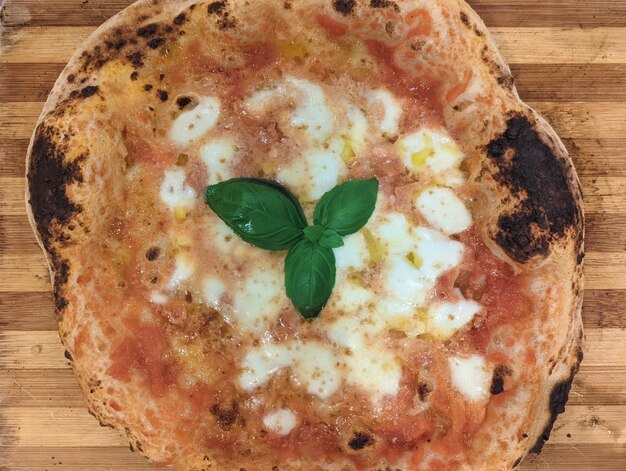 Foto vers gemaakte pizza margherita met basilicum, verse tomatensaus, mozzarella en olijfolie