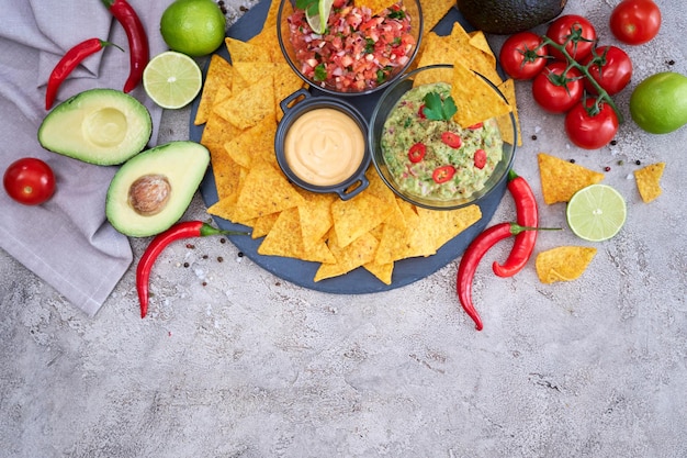 Vers gemaakte salsa en guacamole dipsaus met nacho chips op stenen serveerplank