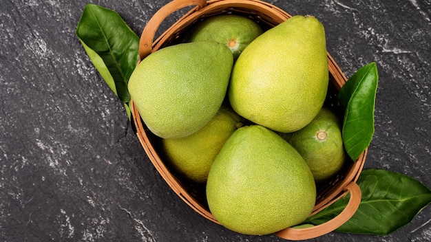 Vers gepelde pomelo pummelo grapefruit shaddock op donkere achtergrond in bamboe mand Herfst seizoensfruit bovenaanzicht plat lag tafelblad schot