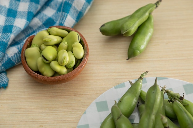 Vers gepelde tuinbonen in een bord op een houten tafel