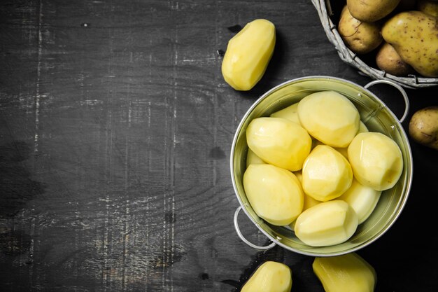 Foto vers geschilde aardappelen op een zwarte achtergrond