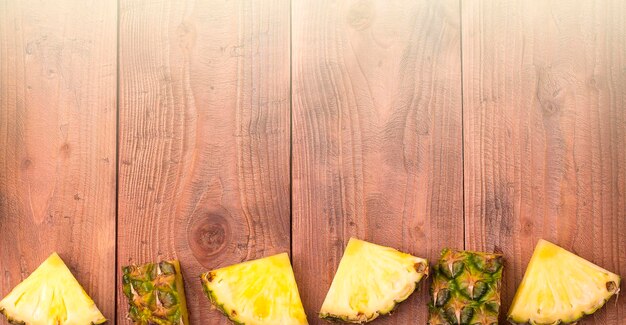 Foto vers gesneden ananas met hele op de houten achtergrond vrije ruimte voor tekst bovenaan