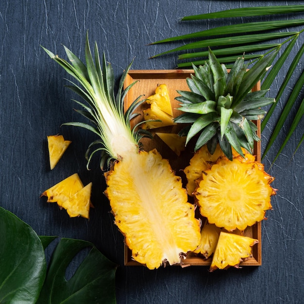 Vers gesneden ananas met tropische bladeren op donkerblauwe achtergrond