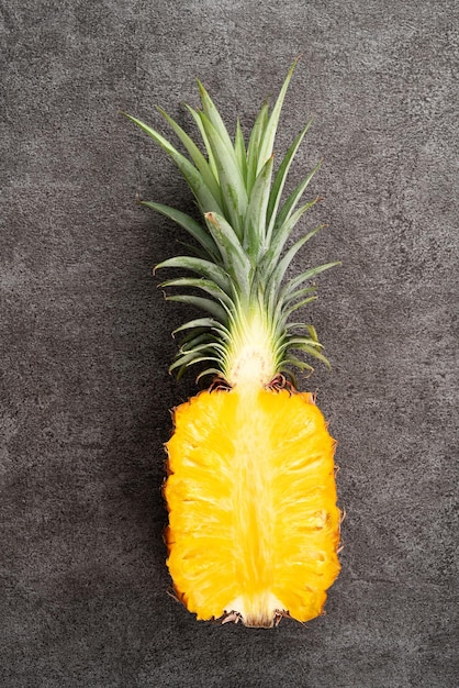 Vers gesneden ananas met tropische bladeren op een donkergrijze achtergrond