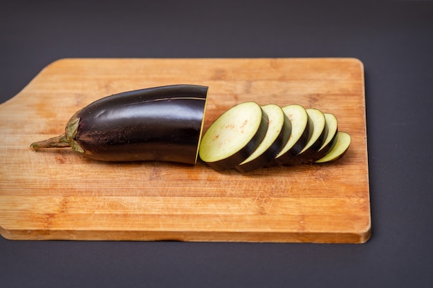 Vers gesneden aubergine op houten snijplank geïsoleerd op zwart.