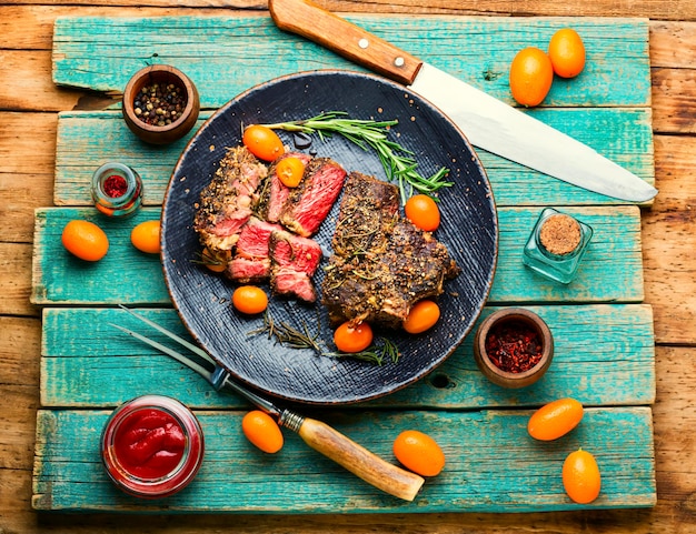 Foto vers gesneden biefstuk geroosterd met kumquat, rozemarijn en kruiden. kalfsentrecote op een bord