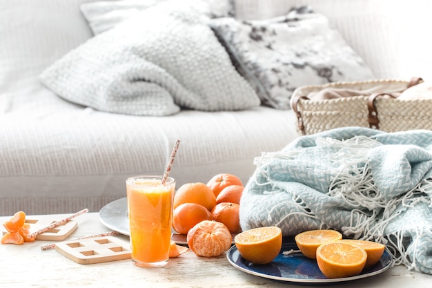 Vers geteelde biologische verse jus d'orange in het huis, met een turquoise deken en een fruitmand