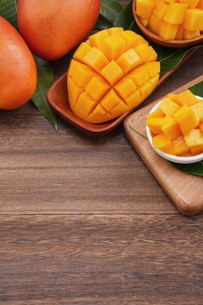 Vers mango mooi gehakt fruit met groene bladeren op donkere houten tafel achtergrond Tropisch fruit ontwerpconcept Plat lag Bovenaanzicht Kopieer ruimte