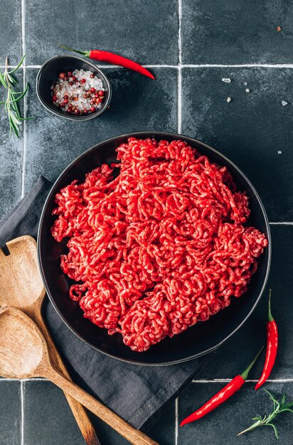 Vers rauw gehakt rundvlees met kruiden en specerijen op een zwart bord