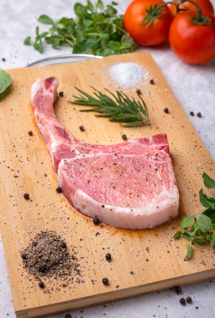 Vers rauw varkensvlees met kruiden en rozemarijn en zwarte peper op houten snijplank