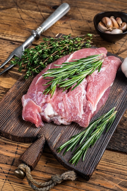 Vers rauw varkensvlees schoudervlees met ingrediënten en kruiden op houten slagersbord. houten tafel. bovenaanzicht.