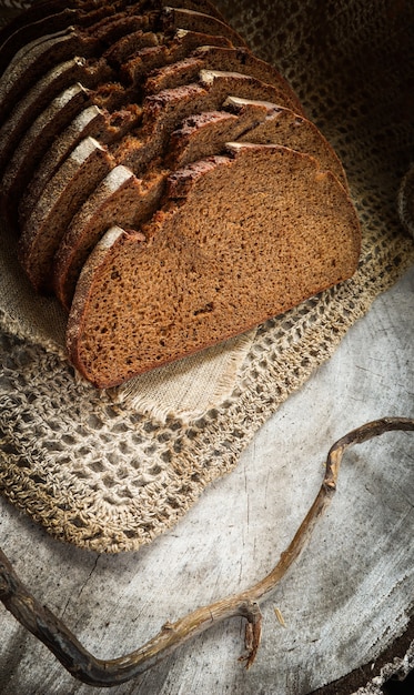 Vers rogge gesneden brood op natuurlijk linnen servet op rustieke houten achtergrond