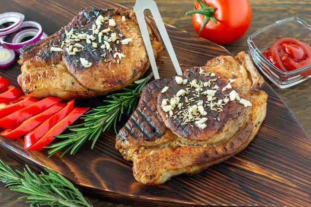 Vers, sappig geroosterd rood vlees op een houten bord, met kruiden en groenten. Restaurant eten, heerlijk gerecht.