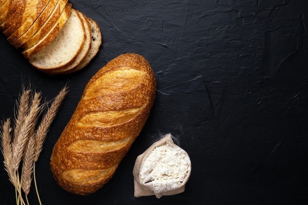 Vers tarwe stokbrood en meel op donkere achtergrond Bovenaanzicht Kopieer de ruimte