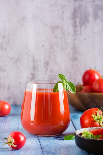 Vers tomatensap met basilicumblaadjes in een glas op tafel Zelfgemaakte biologische drankjes Verticale weergave