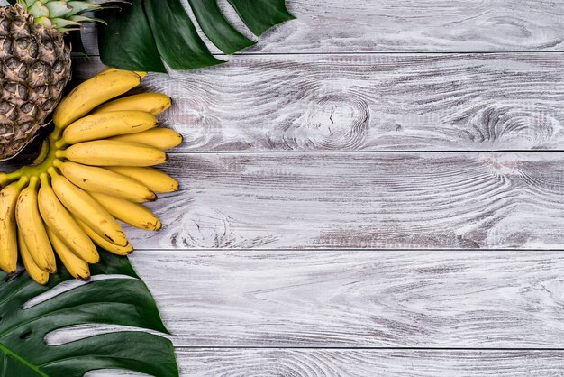 Vers tropisch fruit op hout bovenaanzicht. bananen, ananas, kokos, mango, lychee, kastanjes.