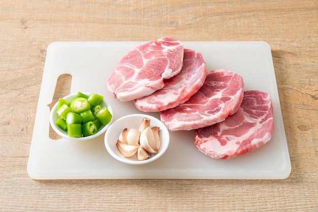 vers varkensnek rauw of kraagvarkensvlees aan boord met ingrediënten voor gemarineerd