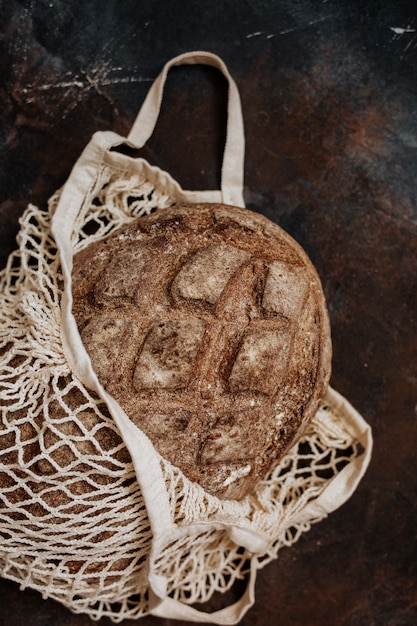 Foto vers volkoren brood in een zak op een donkere achtergrond