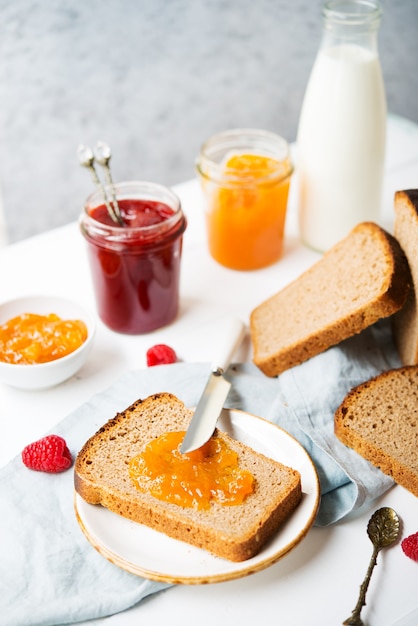 Vers zelfgebakken brood met jam en melk, zelfgemaakte eenvoudig eten, lichte achtergrond