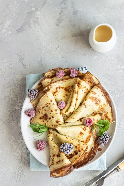 Vers zelfgemaakte Franse pannenkoeken (dunne pannenkoeken) met bevroren bessen en munt voor het ontbijt