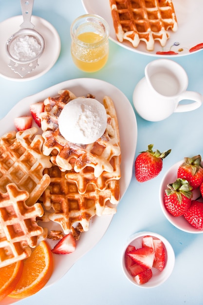 Vers zelfgemaakte gebakken wafels met aardbeien, honing en ijs