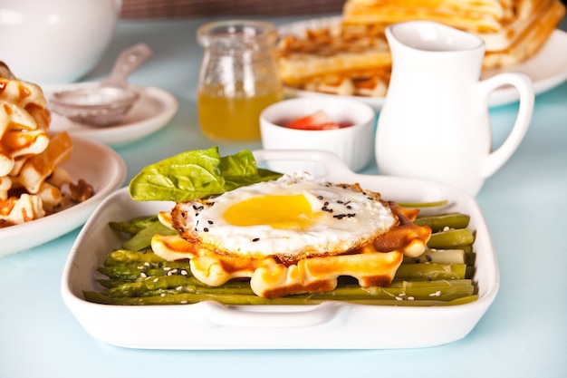 Vers zelfgemaakte gebakken wafels met omelet, spinazieblaadjes en asperges.