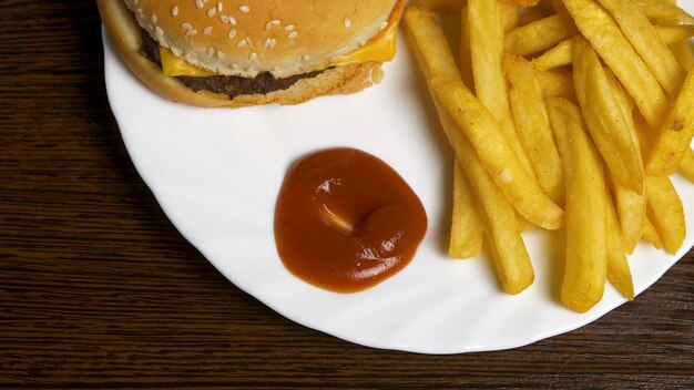 Foto vers zelfgemaakte hamburger met zwarte sesamzaadjes op een wit bord met friet en aardappelen