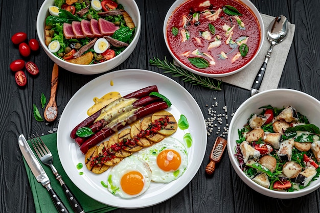 Foto verscheiden voedsel op tafel tomatensoep met mozzarella tonijnsalade roerei met worst diverse gerechten in het restaurant