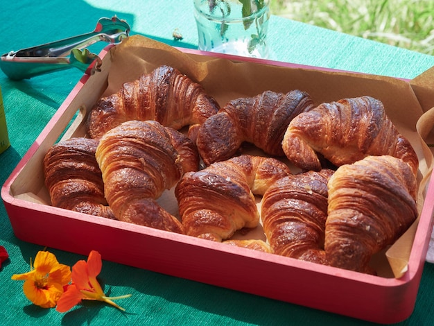 Verscheidene croissants op een rood dienblad op een groen tafelkleed Ontbijtbuffetconcept buiten