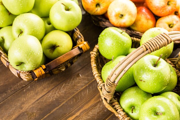 Verscheidenheid aan biologische appels in manden op houten tafel.