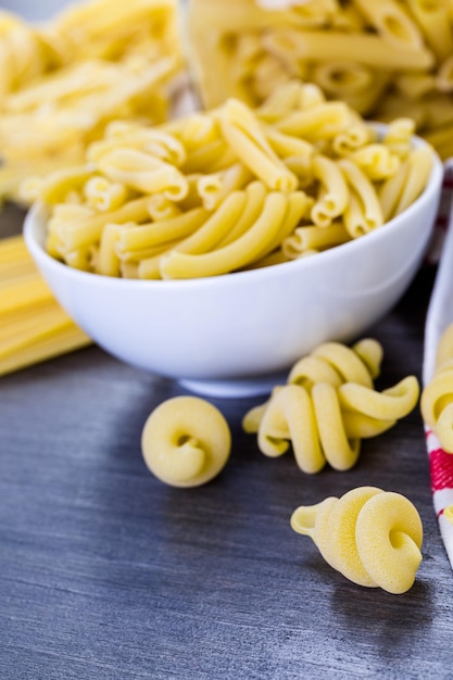 Verscheidenheid aan biologische droge pasta op een houten bord.