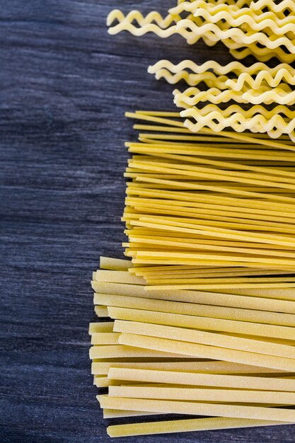 Verscheidenheid aan biologische droge pasta op een houten bord.