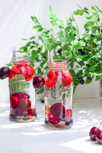 Verscheidenheid aan fruit met detox water in kleine glazen flesjes. Verfrissende zomerdrankjes. Gezond dieetconcept.