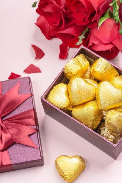Verscheidenheid aan geschenken en chocolaatjes in de vorm van een gouden hart geïsoleerde roze achtergrond Valentine39s concept