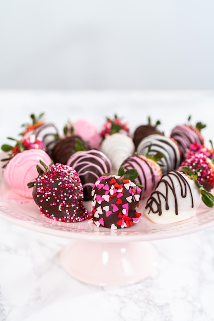 Verscheidenheid aan in chocolade gedompelde aardbeien op een roze taartplateau