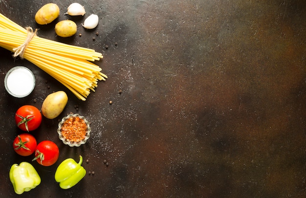 Verscheidenheid aan rauwe pasta met verse tomaten en op bruine achtergrond