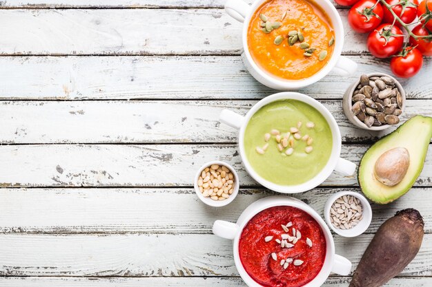 Verscheidenheid aan verschillende kleurrijke groenteroomsoepen in kommen, bovenaanzicht. Concept van gezond eten of vegetarisch eten.