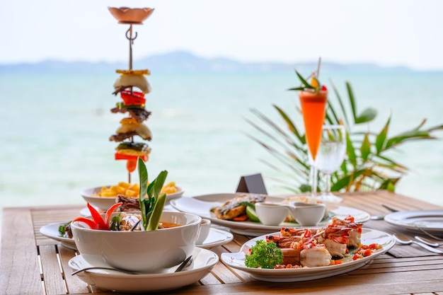 Verscheidenheid aan voedsel geroosterde varkensribbetjes, biefstuk, zeevruchten en pittige soep op eettafel in tropische zee
