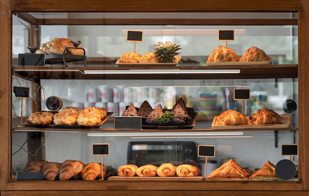 Verscheidenheid gebakken brood en dessert in glazen vitrine bij bakkerijwinkel