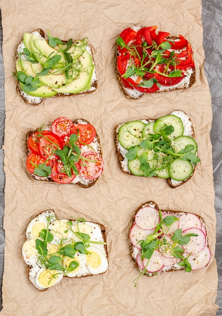 Foto verscheidenheid van mini sandwiches met roomkaas en groenten op platen op papier oppervlak