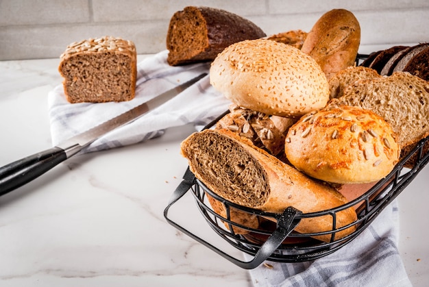 Verscheidenheid van vers zelfgemaakt graan brood, in een metalen mand, wit marmer copyspace