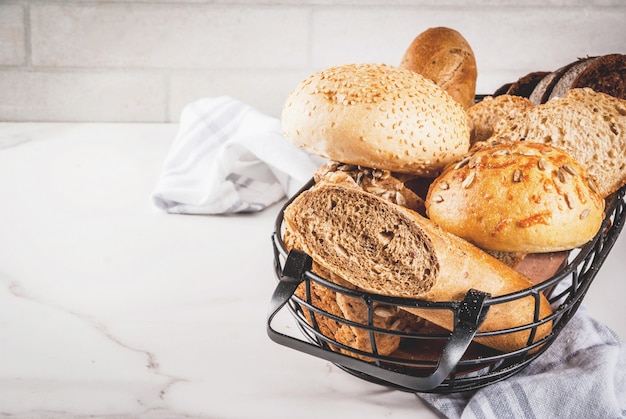 Verscheidenheid van vers zelfgemaakt graan brood, in een metalen mand, wit marmer copyspace