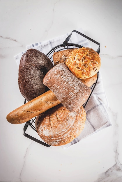 Verscheidenheid van vers zelfgemaakt graan brood, in een metalen mand, witte marmeren copyspace bovenaanzicht