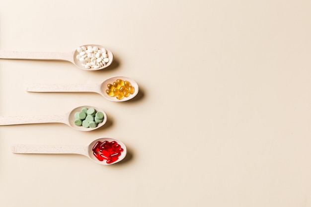 Verscheidenheid van vitamine- en mineraalpillen in houten lepel op gekleurde achtergrond Bovenaanzicht van geassorteerde farmaceutische geneeskundepillen Voedingssupplement gezondheidszorgproduct